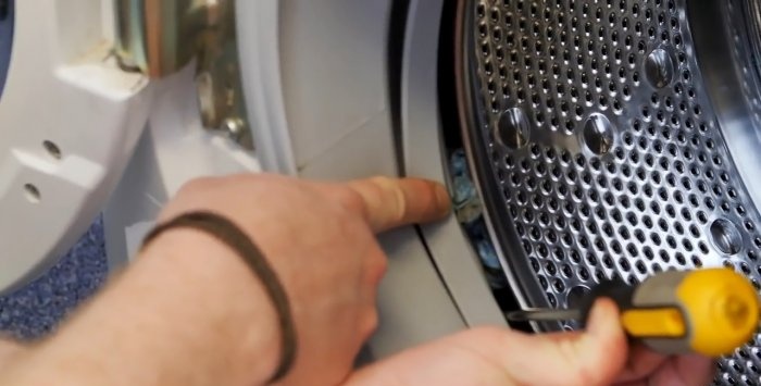 How to remove small objects caught behind the drum from a washing machine